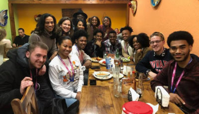 Howard University hopeful apprentices are gathered around a table at a Mexican restaurant smiling.