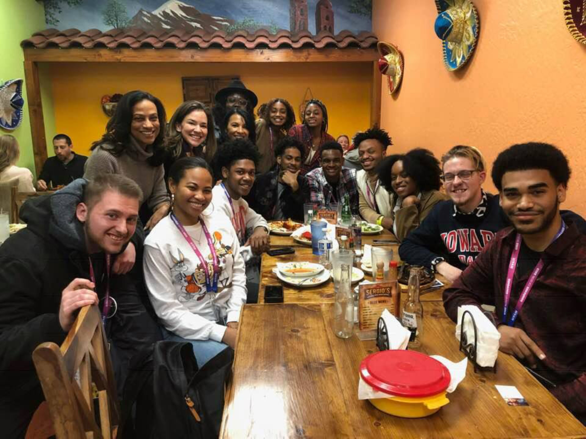 Howard University hopeful apprentices are gathered around a table at a Mexican restaurant smiling.